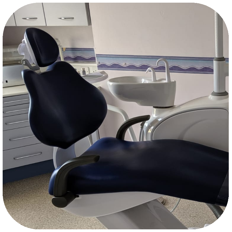 Dental chair in a clinical setting with sink and cabinets.